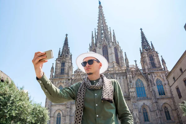 Genç bir adam, bir turist gözlük ve şapka, The Cathedral Holy Cross ve Aziz Eulalia Barcelona, İspanya'nın önünde selfie yapar