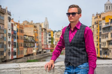 Genç bir adam Girona, İspanya Onyar Nehri yakınında köprüde duruyor