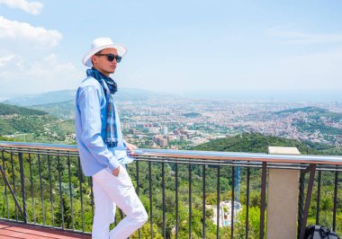 Genç bir adam bir atkı, şapka ve sırt çantası Mount Tibidabo üzerinde duruyor ve Barcelona, İspanya görünümünü hayran 