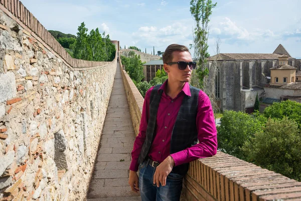 Bir sırt çantası konumu Girona, İspanya kale duvarında (Passeig de la Murala) olan genç bir turist. Girona, manzara kale duvarında görünümünü