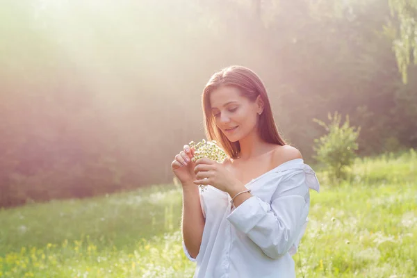 Piękna Młoda Kobieta Białej Koszuli Trzyma Dzikie Kwiaty Słońcu Łące — Zdjęcie stockowe