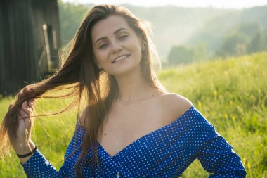 Güzel genç bir kadın yaz mevsiminde çayırda kır çiçekleriyle gülüyor..