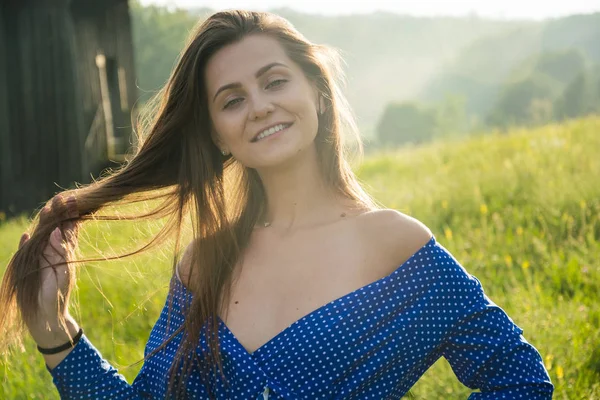 Güzel genç bir kadın yaz mevsiminde çayırda kır çiçekleriyle gülüyor..