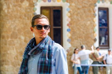 Genç bir adam güneş gözlüklü Guell Park, içinde mimar Gaudi Barcelona, İspanya bir gingerbread house civarındaki standları