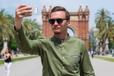Genç bir adam, bir turist gözlük, Catalonia, İspanya Barselona şehir Arc de Triomf yakınındaki selfie yapar