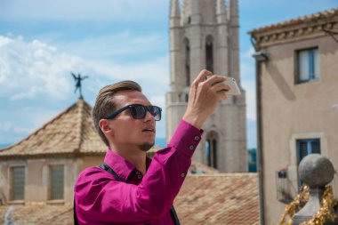 Bir genç adam, turist, Plaza de Catedral Girona, İspanya üzerinde Cathedral yakınındaki bir smartphone resimlerle alır.