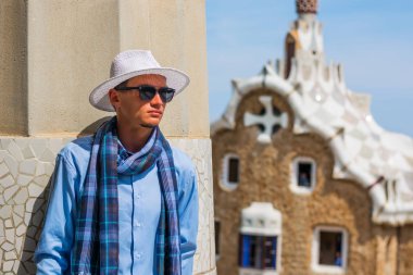 Genç bir adam bir şapka, güneş gözlüğü, eşarp tribünlerde Park Guell, Gaudi, Barselona, İspanya, mimar.