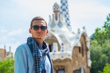 Genç bir adam güneş gözlüklü Guell Park, içinde mimar Gaudi Barcelona, İspanya bir gingerbread house civarındaki standları