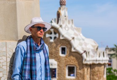 Genç bir adam bir şapka, güneş gözlüğü, eşarp tribünlerde Park Guell, Gaudi, Barselona, İspanya, mimar.