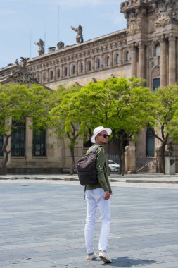 Genç bir adam şapka, güneş gözlüğü port Barcelona'nın liman gümrük arka - bir anıtsal yapı, Barselona, İspanya, yürüyüş içinde