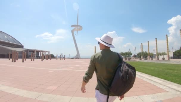 若い男が バルセロナ スペインのマウント Montjuc のバックパックとサンティアゴ カラトラヴァの通信塔とオリンピック リング Anella Olmpica Montjuc — ストック動画