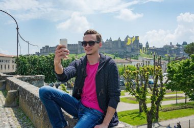 Genç bir adam smartphone görünümü Fransa Carcassonne kale tarafından bir selfie yapar. Fransa'da kale Carcassonne
