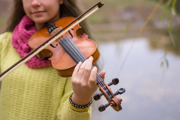 秋紅葉背景で秋の公園でバイオリンを弾く少女 ボケ味は フォア グラウンドでヴァイオリン — ストック写真