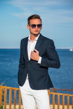 Yakışıklı delikanlı deniz arka plan bir takım elbise ve beyaz pantolon içinde. Moda Model