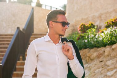 Genç adam beyaz bir gömlek ve güneş gözlüğü merdivenlerden standları