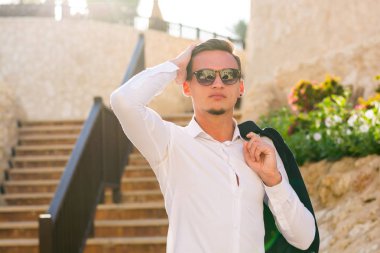 Genç adam beyaz bir gömlek ve güneş gözlüğü merdivenlerden standları