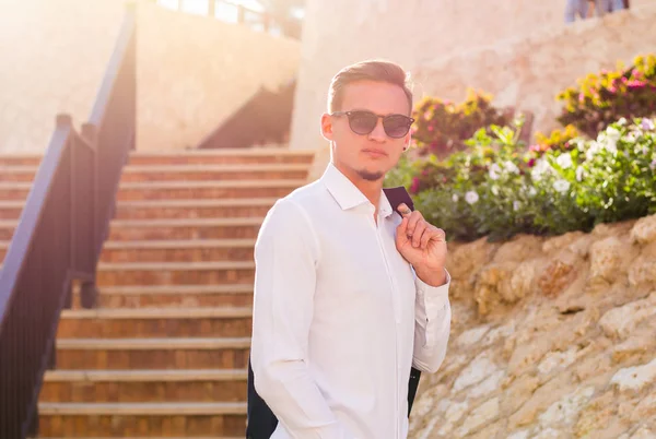 Beyaz bir gömlek ve güneş gözlüğü genç adam merdivenlerden standları