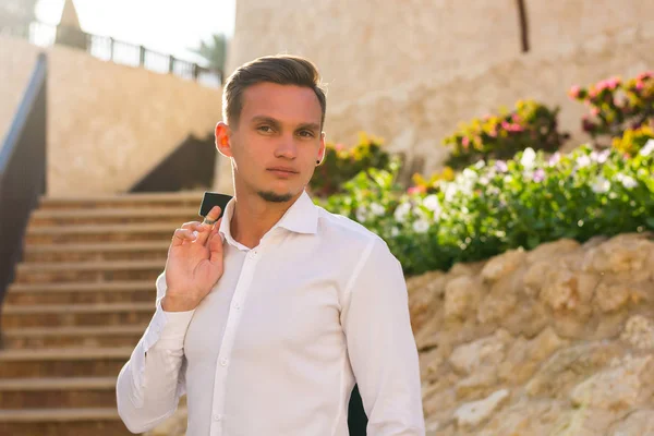 Jeune homme en chemise blanche se tient debout et sourit près des escaliers et — Photo