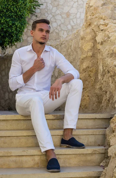 Ung kille i en vit skjorta sitter på trappan — Stockfoto