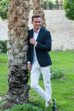 Genç adam beyaz bir gömlek gülüyor yakışıklı beyaz pantolon ve