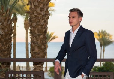 Beyaz bir gömlek, beyaz pantolon ve takım elbise sta yakışıklı delikanlı