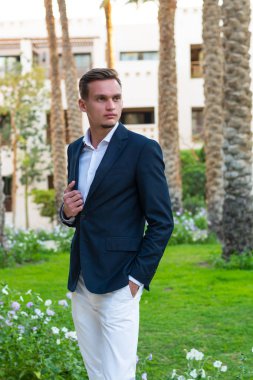 Beyaz bir gömlek, beyaz pantolon ve takım elbise sta yakışıklı delikanlı