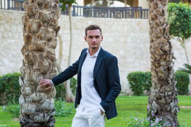 Beyaz bir gömlek, beyaz pantolon ve takım elbise sta yakışıklı delikanlı