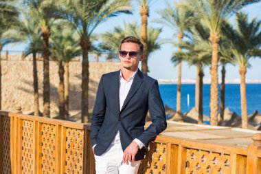 Deniz backgrou bir takım elbise ve beyaz pantolon genç yakışıklı adam