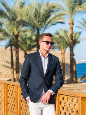 Deniz backgrou bir takım elbise ve beyaz pantolon genç yakışıklı adam