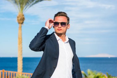 Deniz backgrou bir takım elbise ve beyaz pantolon genç yakışıklı adam