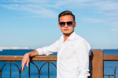 Genç yakışıklı adam beyaz bir gömlek ve beyaz pantolon deniz b