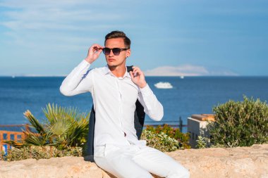 Genç yakışıklı adam beyaz bir gömlek ve beyaz pantolon deniz b