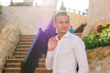 Beyaz gömlekli bir genç adam standları ve gülümsüyor merdivenlerden ve