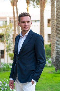 Beyaz bir gömlek, beyaz pantolon ve takım elbise sta yakışıklı delikanlı