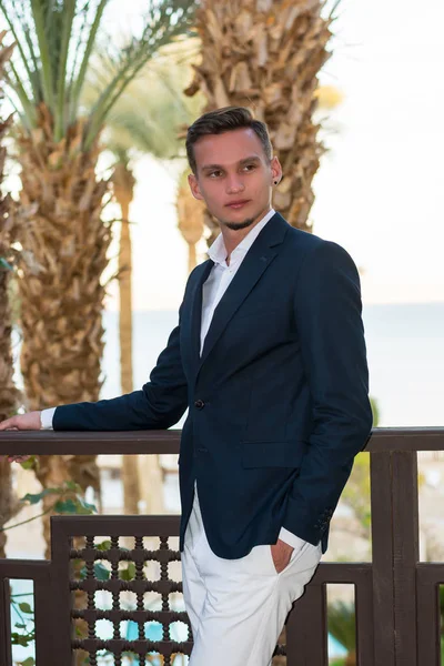 Young handsome man in a white shirt and suit stands on the balco — Stock Photo, Image