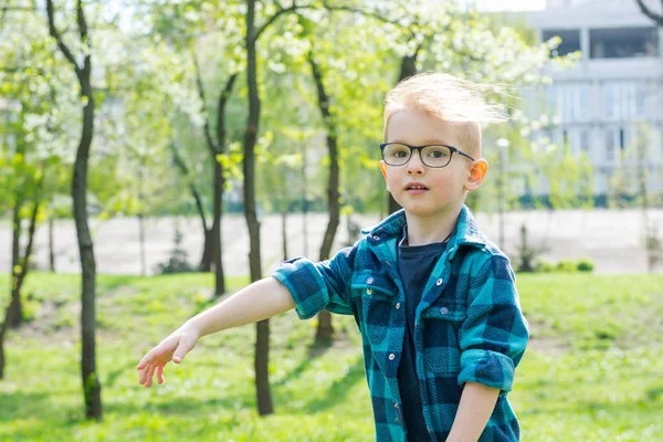 Мальчик в очках бегает в весеннем парке — стоковое фото