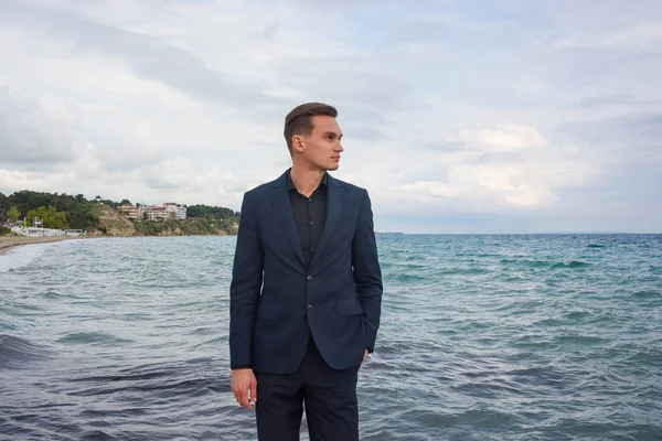 Joven hombre guapo en un traje en el fondo del mar y vista de t — Foto de Stock