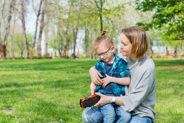 Маленький мальчик и его мама играют с игрушечной машиной в парке в спрее — стоковое фото