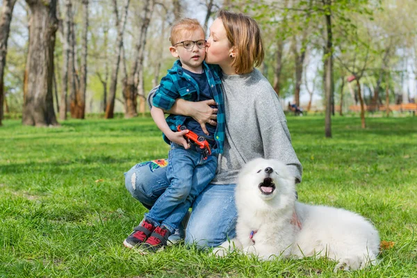 Mama i jej syn z puszystym psem Samoyed w parku wiosną — Zdjęcie stockowe
