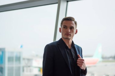Takım elbiseli genç bir adam havaalanında uçaklar da duruyor bac
