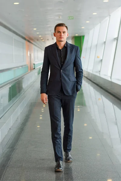 En ung man i kostym går längs flygplats korridoren — Stockfoto