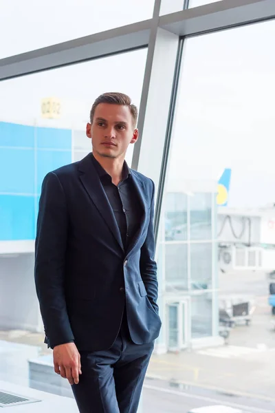 Un jeune homme en costume se tient à l'aéroport près de la fenêtre à t — Photo