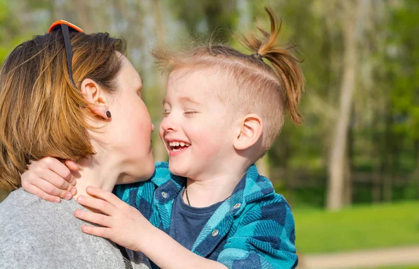 Мальчик обнимает маму и смеется в парке. — стоковое фото