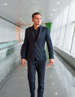 Takım elbiseli, sırt çantası ve bileti olan genç bir adam.