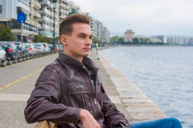 Genç yakışıklı adam, turist, Thessa 'nın rıhtımında oturuyor.