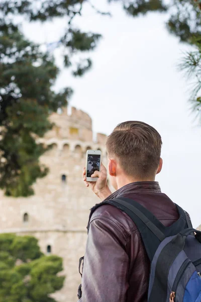 Bonito homem, turista, com mochila tirando fotos em um smartp — Fotografia de Stock
