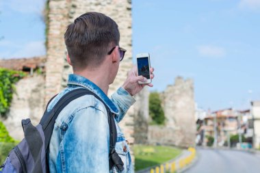 Sırt çantalı genç, yakışıklı bir adam, bir turistin üstünde fotoğraf çekiyor. 