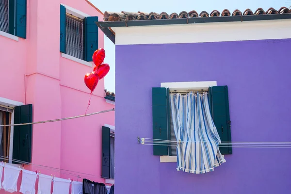 Window with curtains, heart-shaped balloons and colorful houses