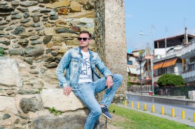 Genç bir adam Yukarı Kale'deki Trigonion Kulesi'nin yanında oturuyor. 