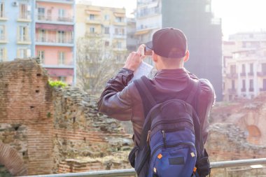 Genç adam, turist, sırt çantası ile bir akıllı telefon üzerinde fotoğraf çekmek